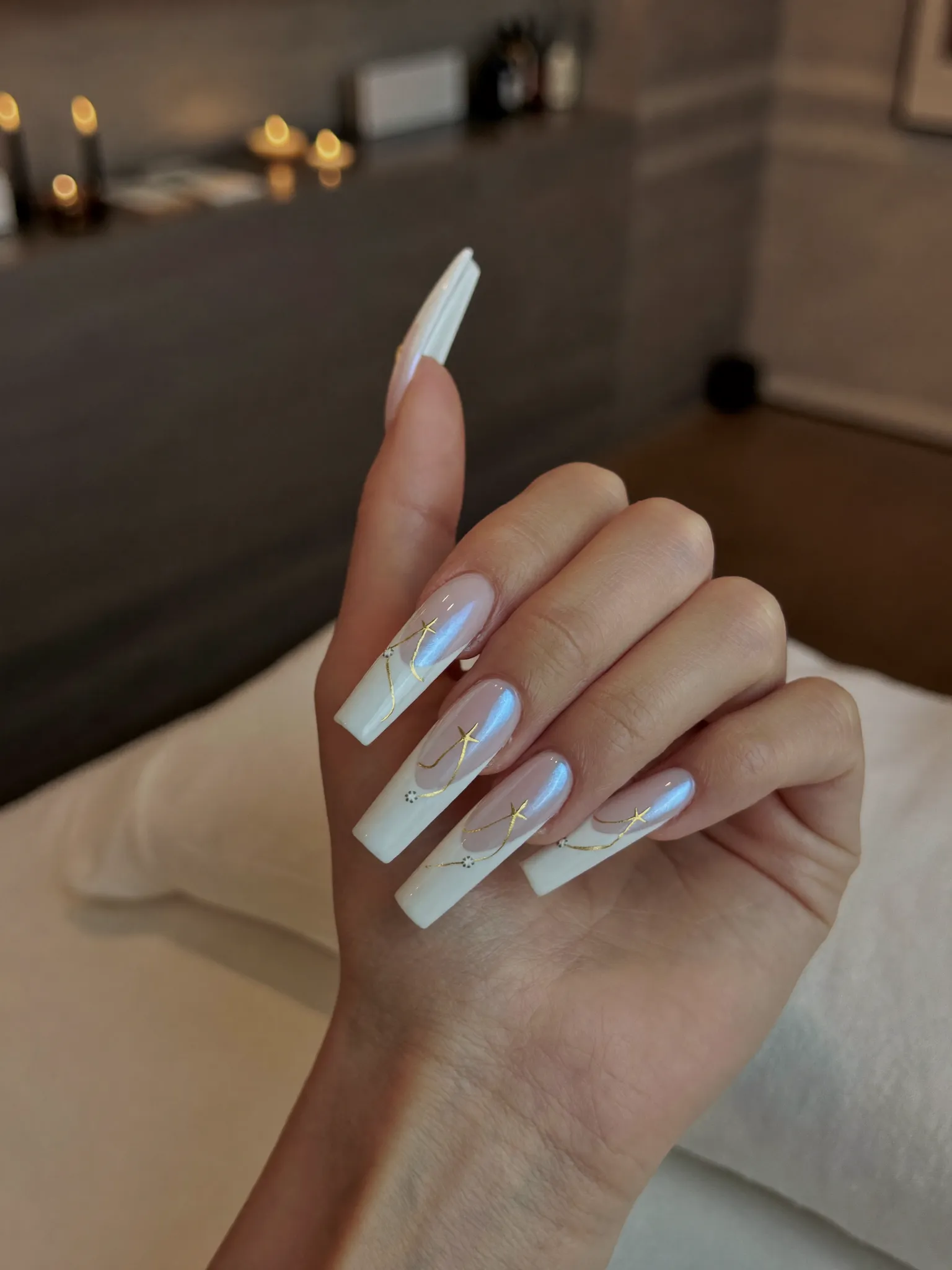 Custom nail art with blush, pearl white, and gold linework